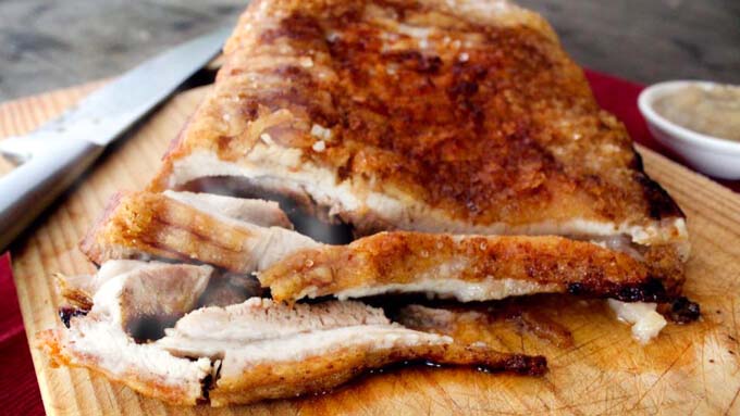 Slices of Roast Pork Belly On a Wooden Chopping Board.