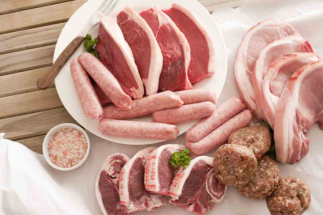 Plate and Table Full of Meat - Sausages, Pork Chops, Meatballs.