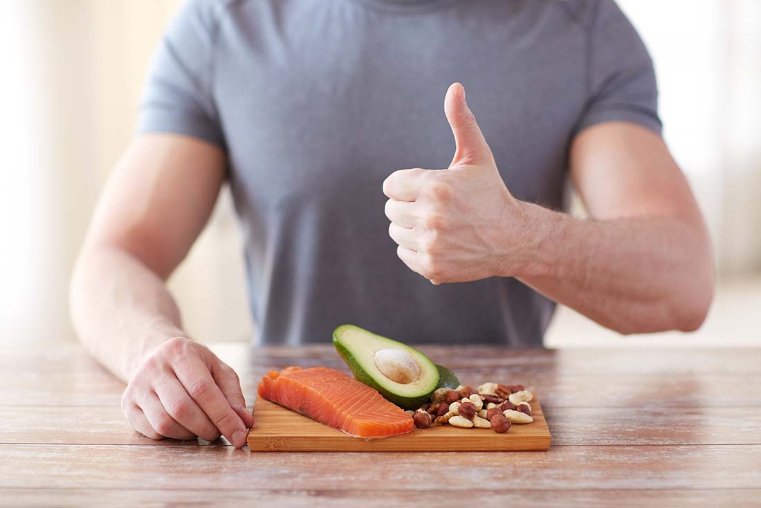 A Man With Salmon, Avocado and Nuts Doing a 'Thumbs Up' Motion. 