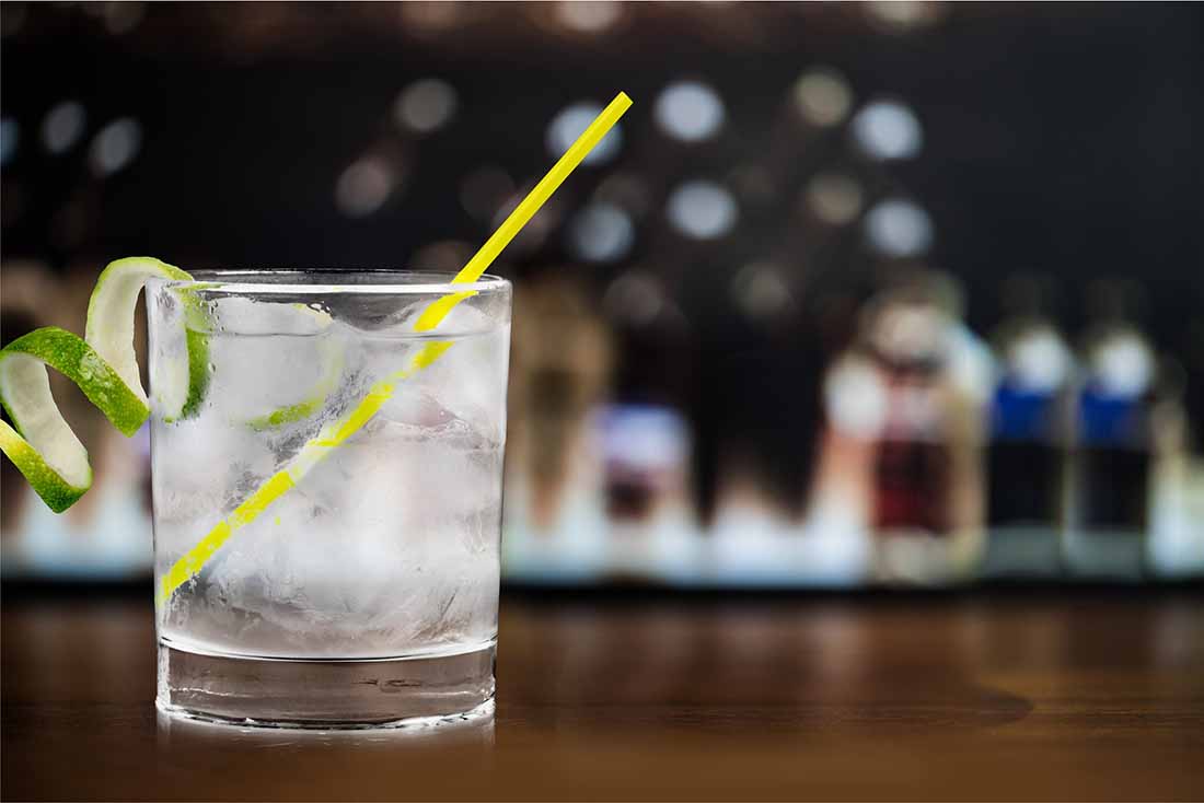 A Glass of Gin and Tonic With a Yellow Straw.