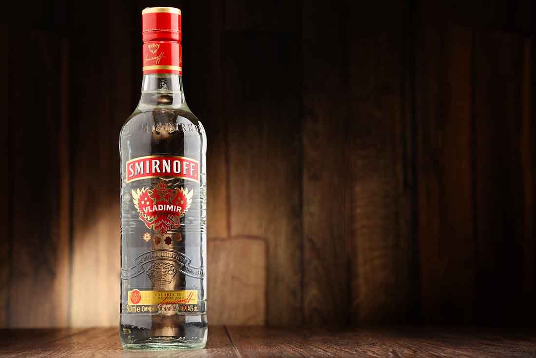 A Glass Bottle of Smirnoff Vodka on a Wooden Surface.