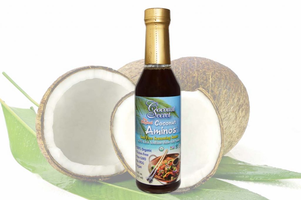 A Bottle of Coconut Aminos Next To a Coconut.