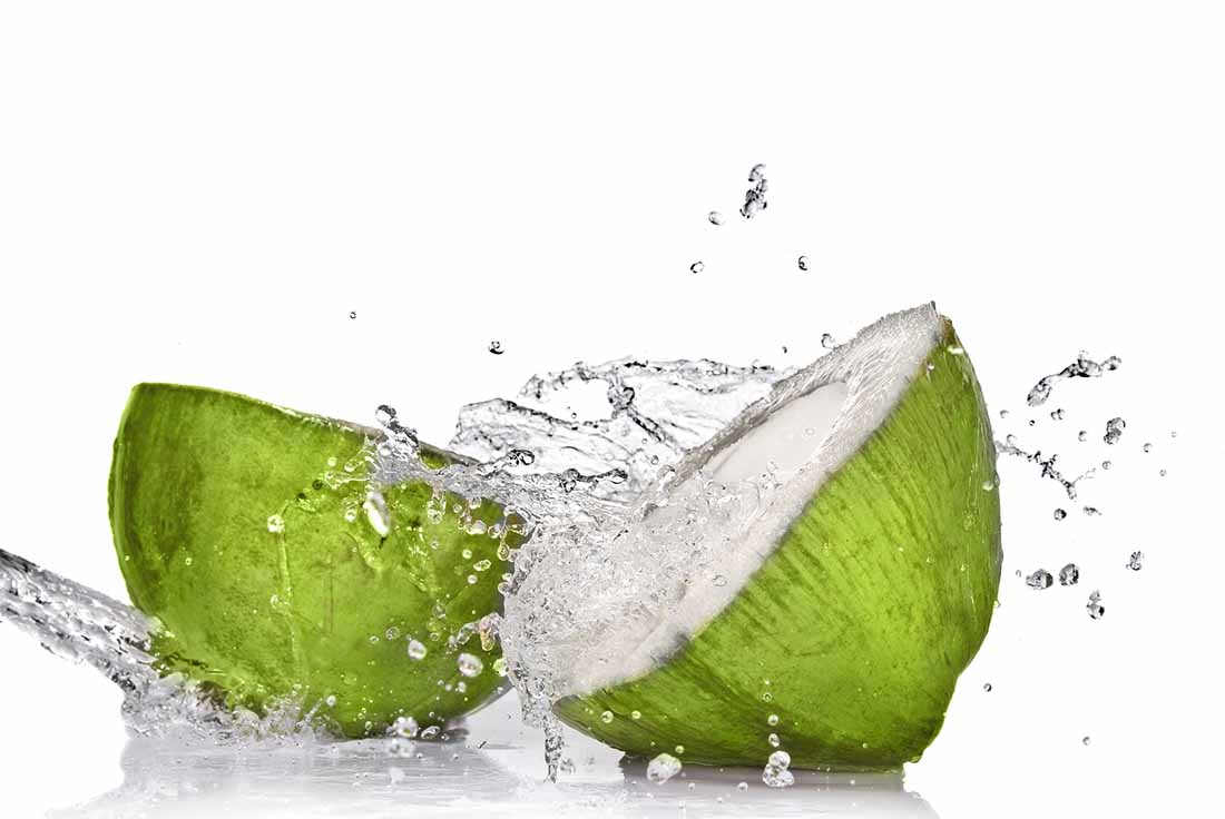 A Fresh Coconut Breaking in Half With Water Flying From the Middle.