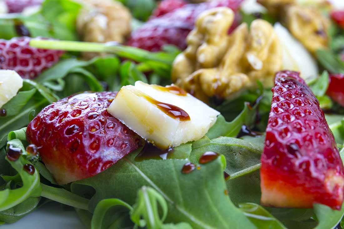 Salad Featuring Leafy Greens, Strawberries, Coconut Vinegar and Cheese.