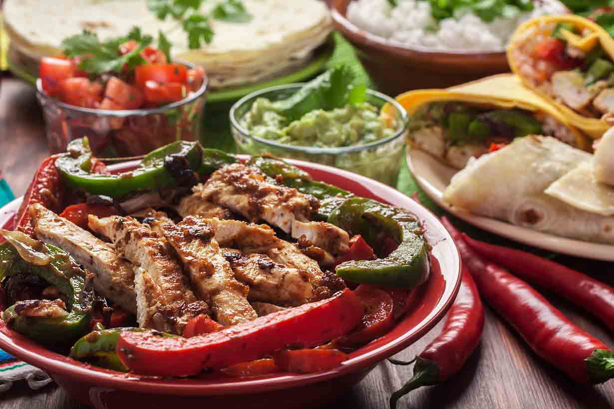 A Table of Healthy Food Including Meat, Vegetables and Guacamole.