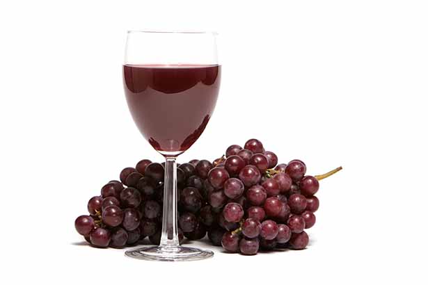 A Glass of Red Wine Next To a Bunch of Grapes.