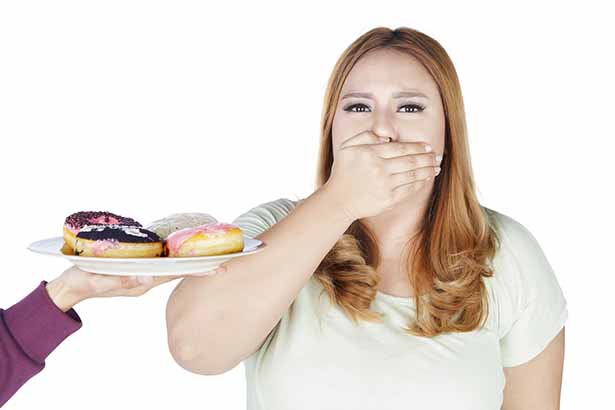 A Woman Covering Her Mouth With Her Hand When Offered a Plate of Refined Carbs.