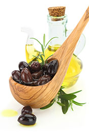 Picture of Kalamata Olives With an Olive Oil Bottle in the Background.