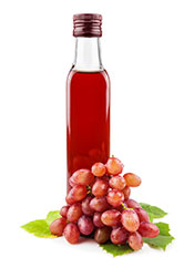 Bottle of Red Wine Vinegar Next to Some Red Grapes.