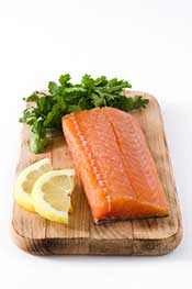 A Salmon Fillet On a Wooden Board Next To Lemon Slices.