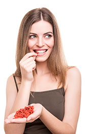 Picture of a Young Woman Eating Goji Berries From Her hand.