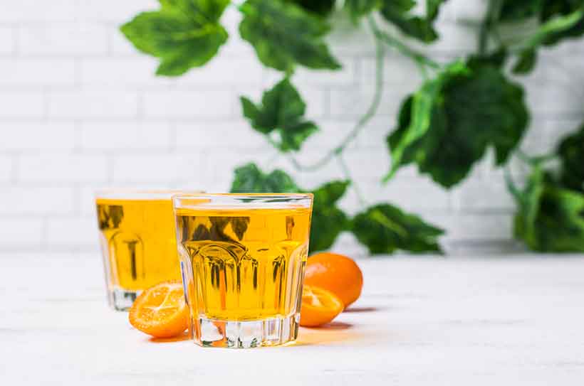 Picture Showing Two Cocktail Glasses Next to Kumquat Halves.