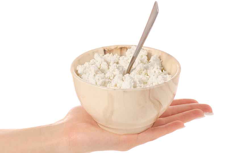 A Woman Holding a Bowl of Cottage Cheese In Her Hand.