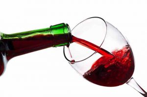Pouring a Glass of Red Wine. A Glass of Red Wine Being Poured From a Green Bottle.