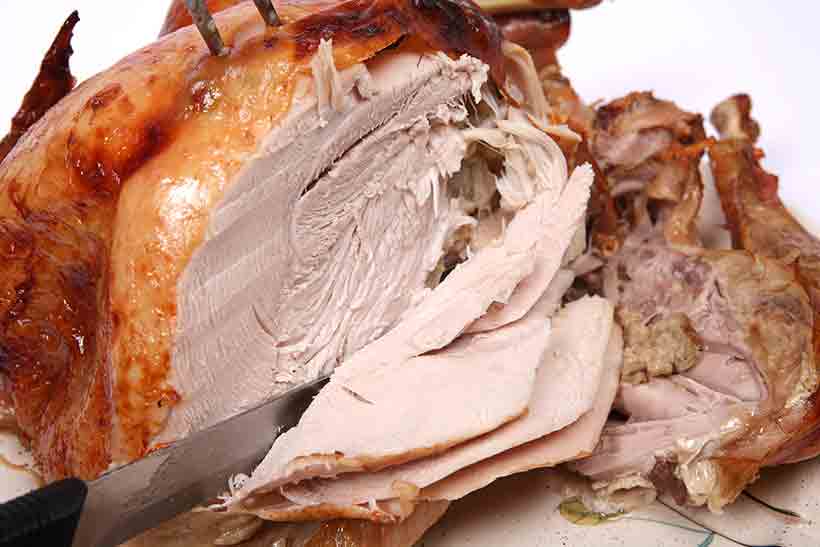 A roasted turkey being carved with light and dark turkey meat both visible.