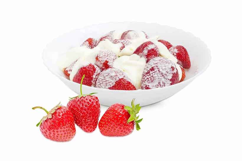 A Bowl of Strawberries With Heavy Cream Poured on Top.