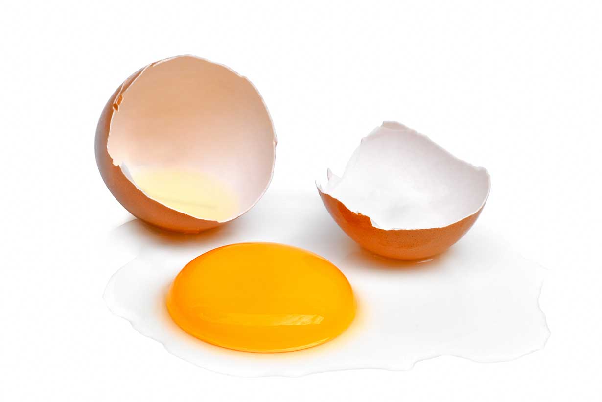 An Egg shell Cracked In Two With the Egg Yolk In the Middle.