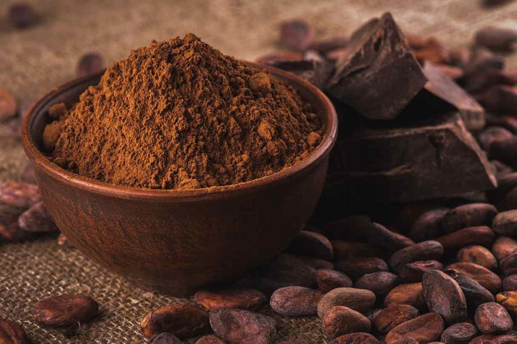 A Bowl of Cocoa Powder, Next To Cocoa Beans.