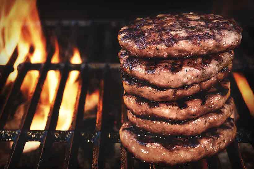 Six Flame-Grilled Beefburger Patties On a Grill.