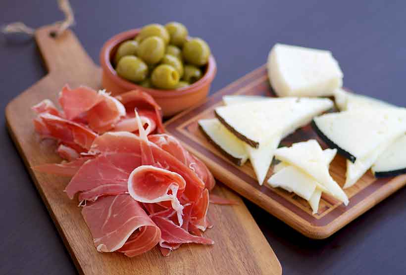 Cold Cuts of Meat, Cheese and Green Olives On a Wooden Board.