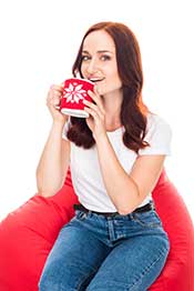 A Woman Sat Down Smiling With a Cup of Black Tea.