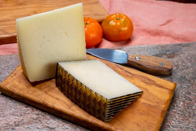 Spanish Manchego Cheese On a Wooden Board.