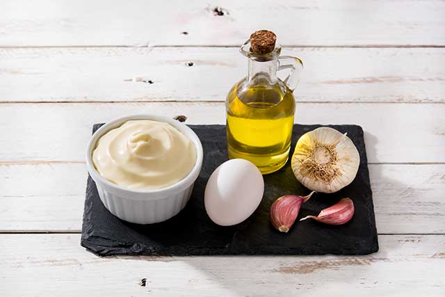 Aioli Sauce and the Ingredients Used To Make It On a Wooden Table.