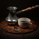 A cup of coffee and roasted coffee beans on a wooden table.