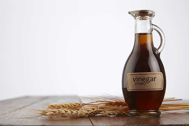 Malt Vinegar in a Glass Bottle on a Wooden Surface.