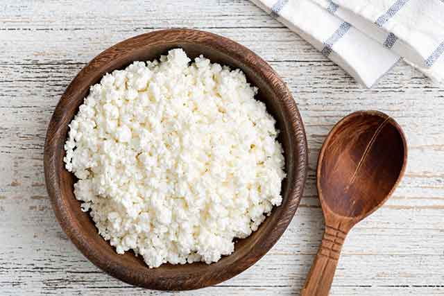 Ricotta Cheese In a Wooden Bowl With a Wooden Spoon.