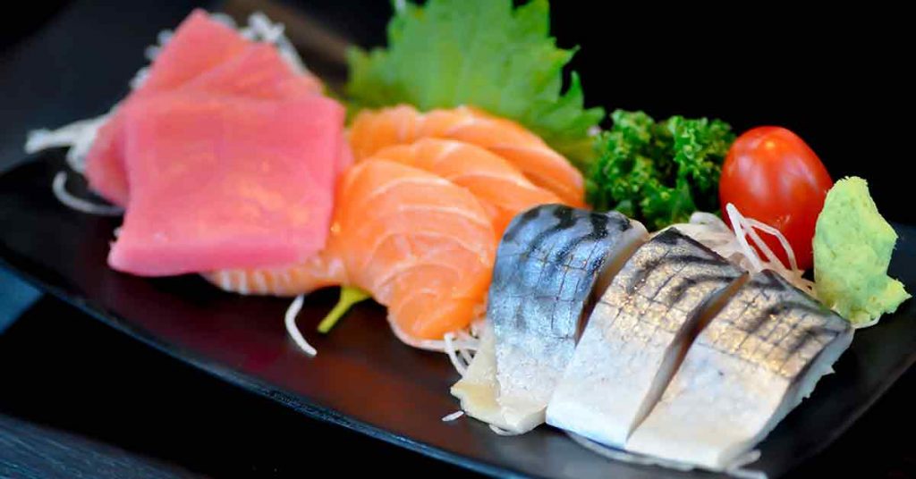 Various slices of raw oily fatty fish, including salmon, tuna, and mackerel.