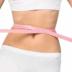 A woman with a tape measure around her waist - weight loss theme.