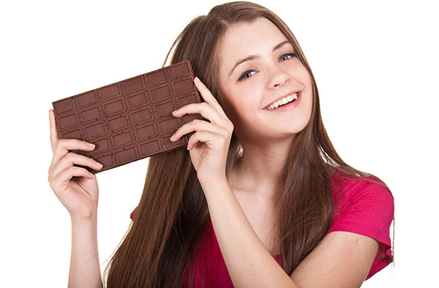 Young Woman Eating Dark Chocolate With a Happy Smile.