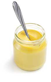 A Glass Jar of American Yellow Mustard With a Spoon In It.