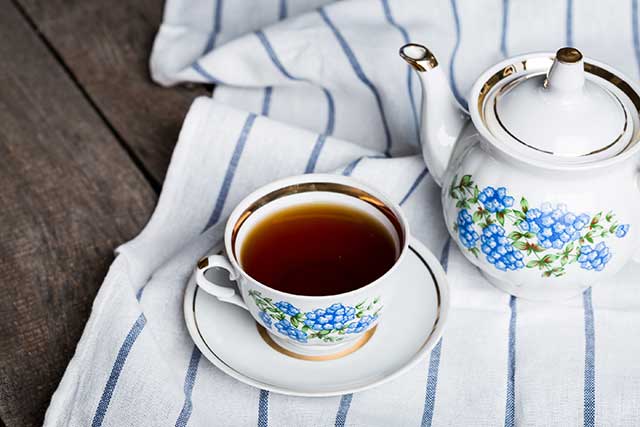 A Freshly Made Cup of Black Tea Next To a Teapot.