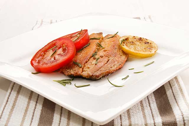 Grilled Kipper On a Plate With Lemon and Tomato.