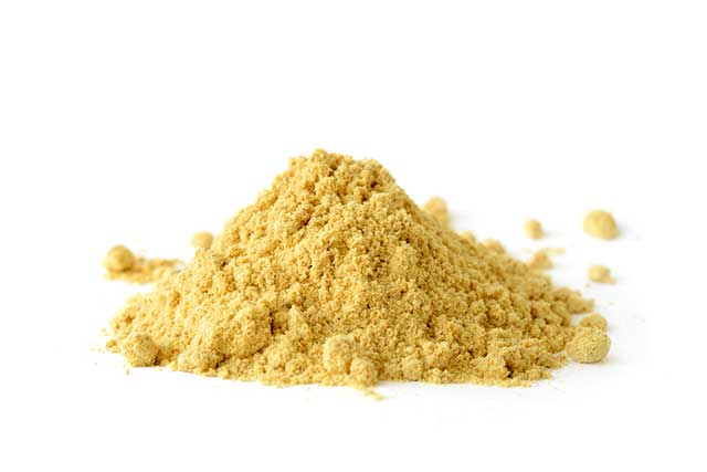 A Pile of Dry Ground Mustard Powder With a White Background.