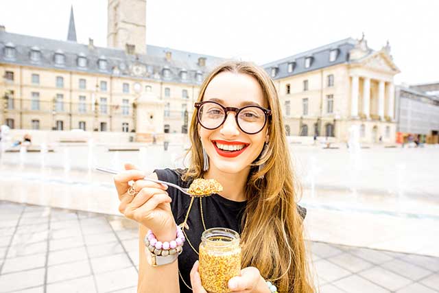 A Young Woman Eating Prepared Mustard By the Spoon.