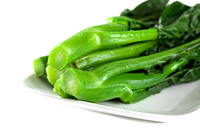 Several Stems of Gai Lan (Chinese Broccoli) On a Plate.