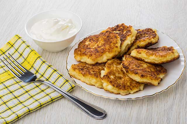 Cottage Cheese Pancakes On a Plate With Sour Cream Side.