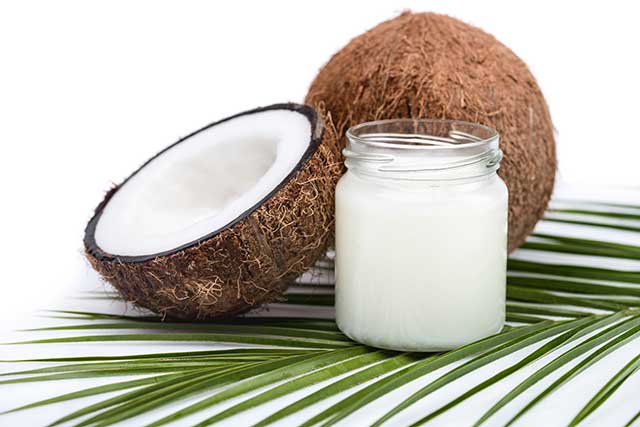 A Jar of Coconut Oil Next To Half a Coconut.