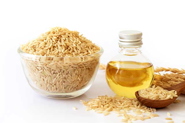 Rice Bran Oil Next To a Bowl of Brown Rice.