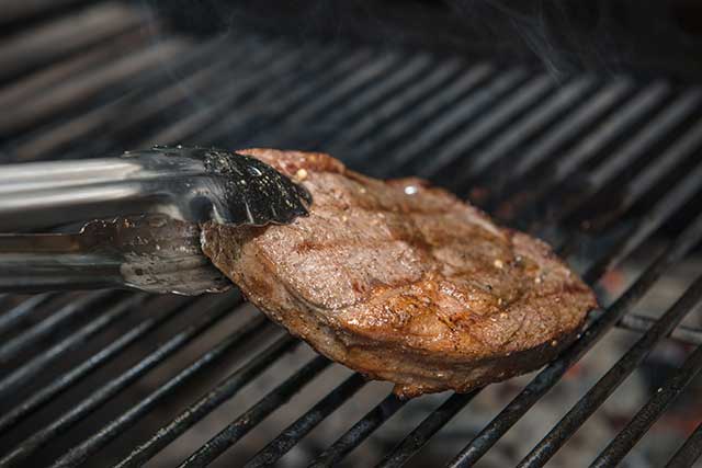 Flipping Ribeye Steak With Tongs.