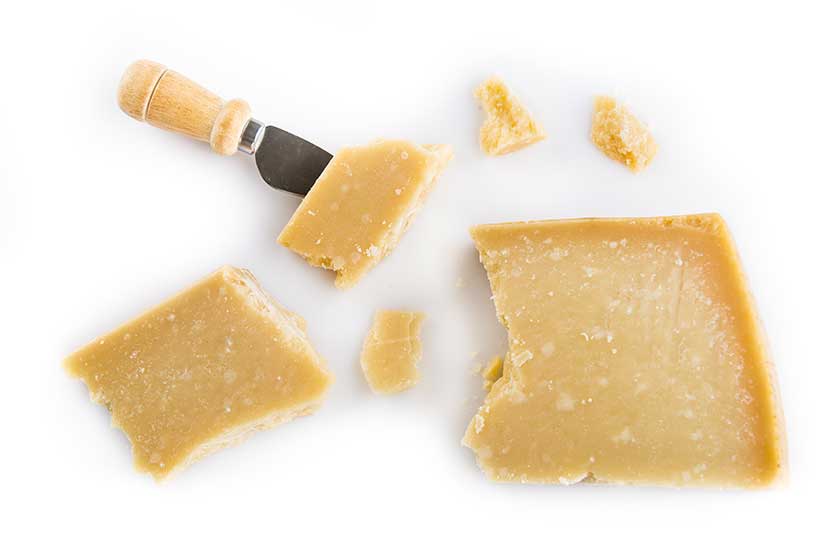 Pedazos de Parmigiano-Reggiano con un cuchillo para queso.