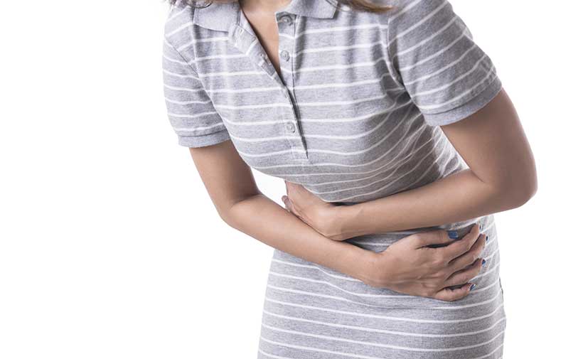 Mujer agachada que experimenta dolor de estómago.