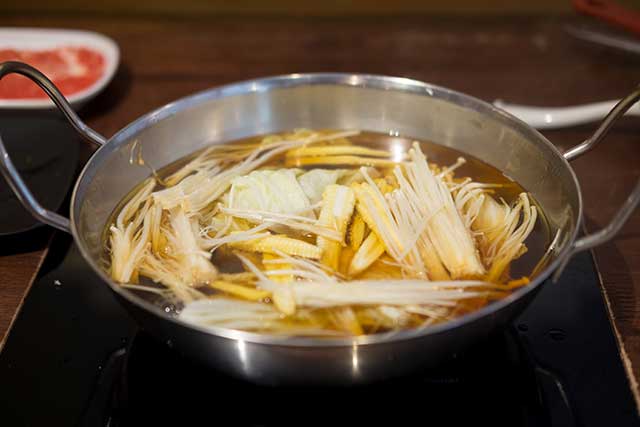 A Bowl of Soup Containing Enoki Noodles.