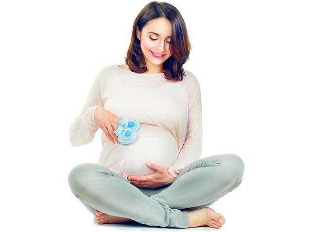 A Pregnant Woman Holding Her Stomach and Smiling.