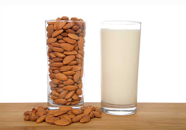 Thick Glass of Almond Cream Next To a Glass of Almonds.