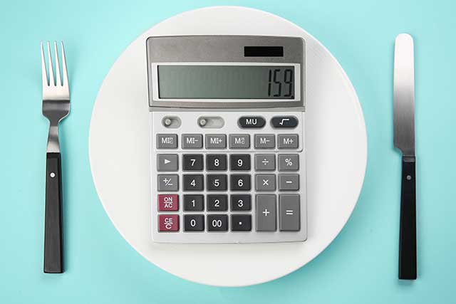 Calculator On a Plate With Knife and Fork Representing Counting Calories.