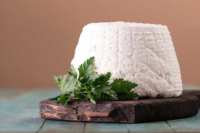 Fromage ricotta frais sur une planche de bois.